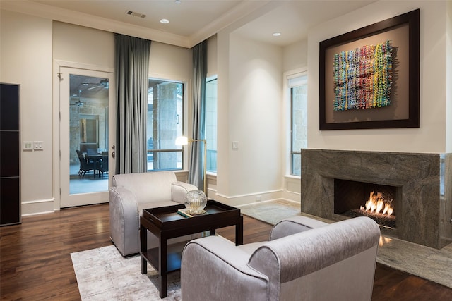 living room with a high end fireplace, a wealth of natural light, crown molding, and dark hardwood / wood-style floors