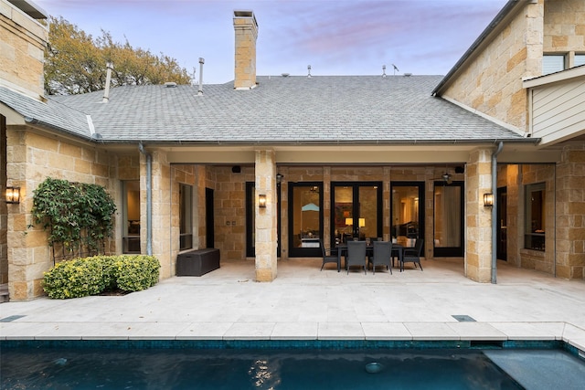 back house at dusk featuring a patio area