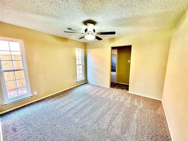 carpeted empty room featuring a textured ceiling and ceiling fan