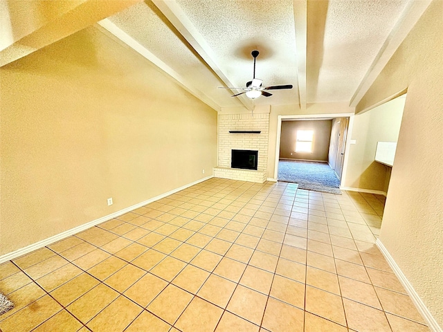 unfurnished living room with ceiling fan, a brick fireplace, lofted ceiling, a textured ceiling, and light tile patterned flooring