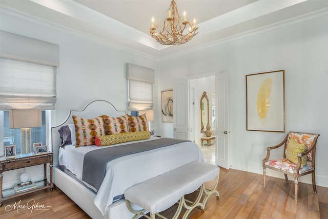 bedroom with hardwood / wood-style flooring, a notable chandelier, crown molding, and a tray ceiling