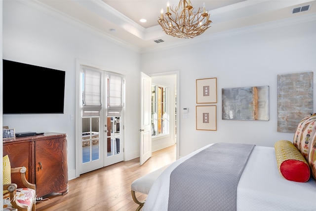 bedroom with access to outside, light hardwood / wood-style flooring, a raised ceiling, a notable chandelier, and ornamental molding