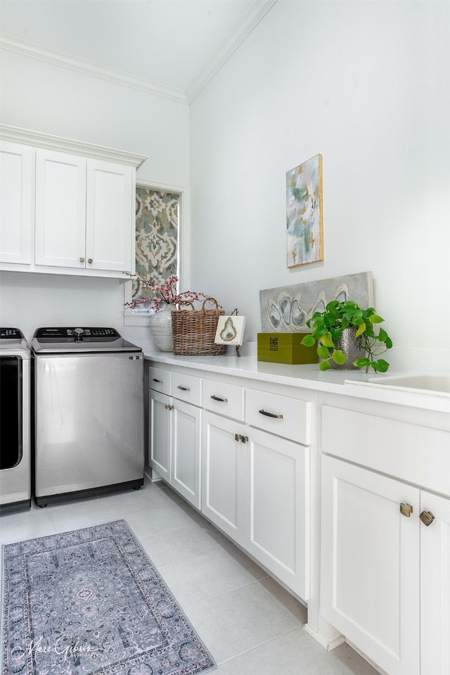 clothes washing area featuring washing machine and clothes dryer, crown molding, light tile patterned floors, and cabinets