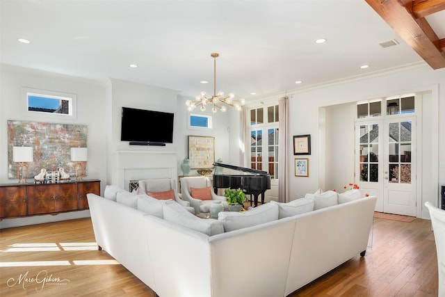 living room featuring french doors, a fireplace, a baseboard heating unit, light hardwood / wood-style flooring, and an inviting chandelier