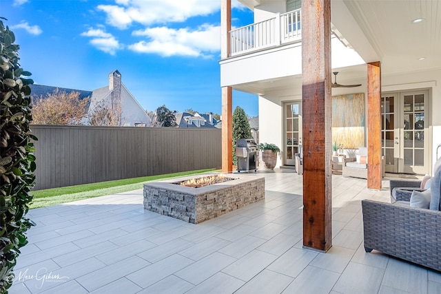 view of patio with an outdoor fire pit, french doors, and a balcony