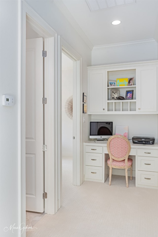 carpeted office with built in desk and crown molding