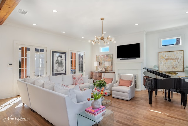 living room with an inviting chandelier, ornamental molding, and light hardwood / wood-style floors