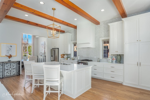 kitchen featuring stainless steel appliances, white cabinets, sink, and a kitchen island with sink