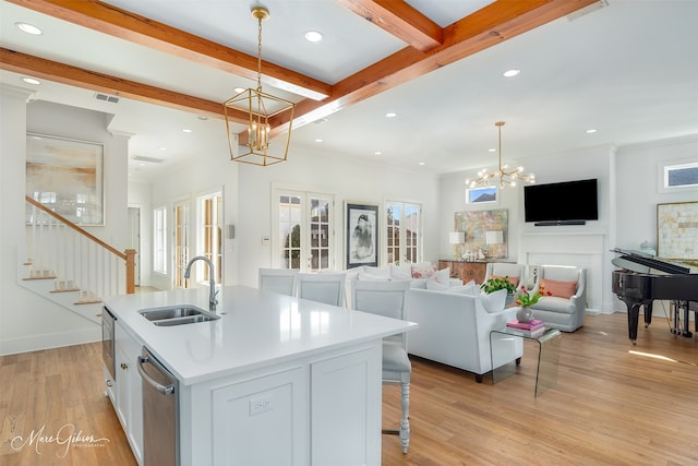 kitchen with hanging light fixtures, an island with sink, beamed ceiling, sink, and an inviting chandelier