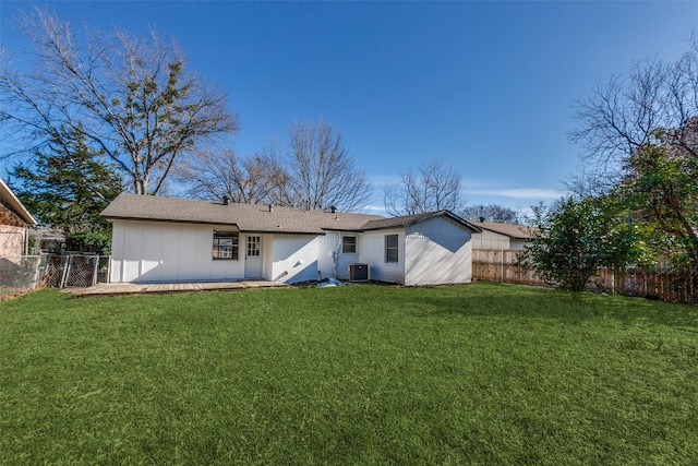 rear view of house with a fenced backyard, central AC, and a yard