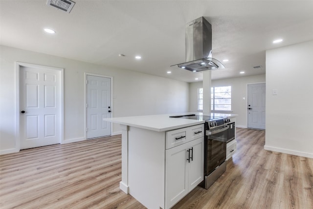 kitchen with visible vents, white cabinets, electric stove, light countertops, and a center island with sink