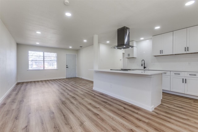 kitchen with light countertops, open floor plan, white cabinets, a kitchen island, and ventilation hood