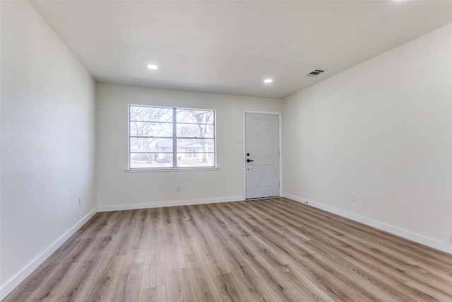 empty room with light wood-style floors, recessed lighting, visible vents, and baseboards