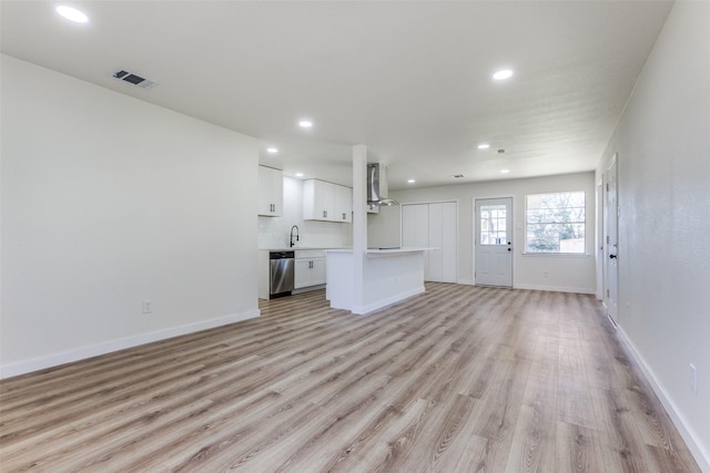 unfurnished living room featuring recessed lighting, visible vents, light wood-style floors, a sink, and baseboards