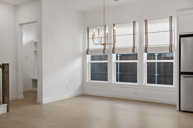 unfurnished dining area featuring light hardwood / wood-style flooring and a chandelier