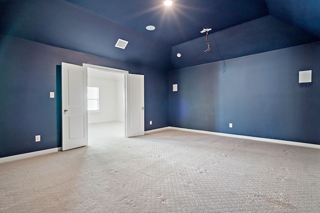 empty room featuring light colored carpet and vaulted ceiling