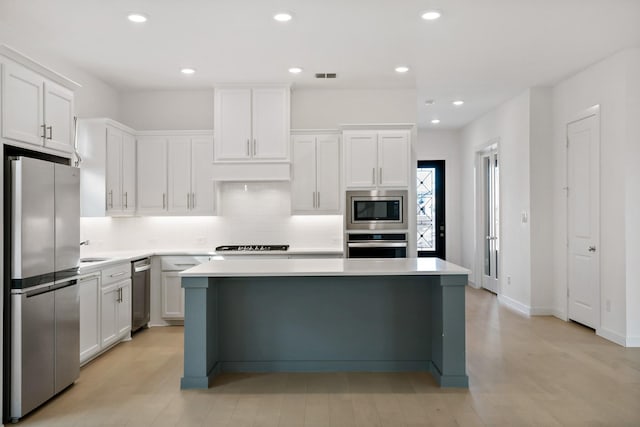 kitchen featuring stainless steel appliances, sink, white cabinets, a center island, and tasteful backsplash