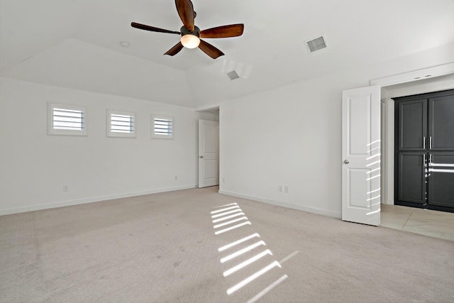 spare room featuring vaulted ceiling, light colored carpet, and ceiling fan