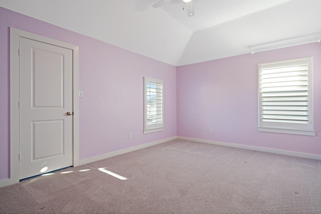 empty room with lofted ceiling, ceiling fan, a wealth of natural light, and light carpet