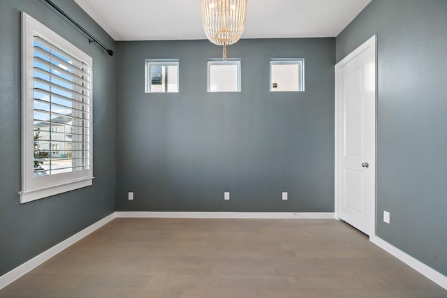 unfurnished room featuring hardwood / wood-style floors and a chandelier