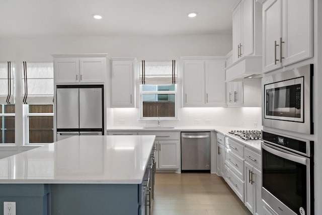 kitchen featuring stainless steel appliances, sink, white cabinetry, decorative backsplash, and a kitchen island