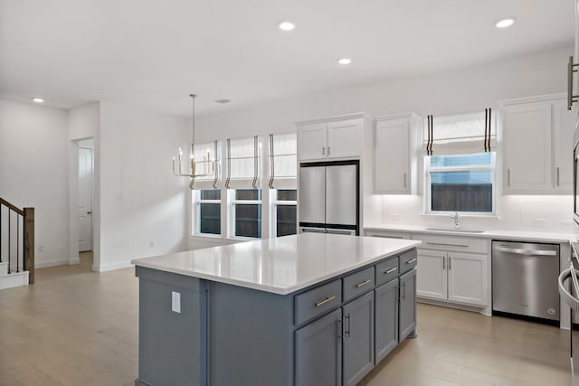 kitchen featuring sink, stainless steel appliances, white cabinetry, and a center island