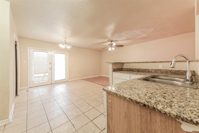 kitchen with sink, french doors, light tile patterned flooring, ceiling fan with notable chandelier, and hanging light fixtures