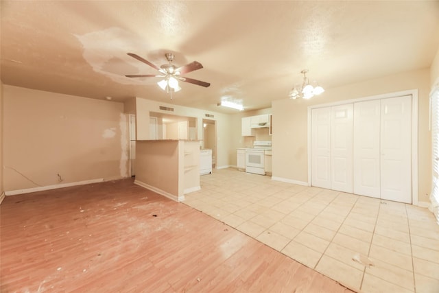 unfurnished living room featuring ceiling fan with notable chandelier and light hardwood / wood-style flooring