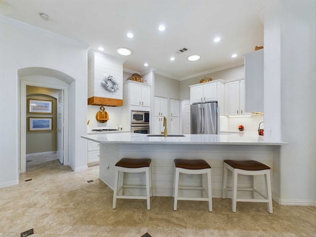 kitchen with kitchen peninsula, a kitchen bar, crown molding, white cabinets, and appliances with stainless steel finishes