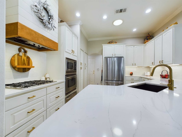 kitchen featuring light stone counters, backsplash, white cabinets, appliances with stainless steel finishes, and ornamental molding