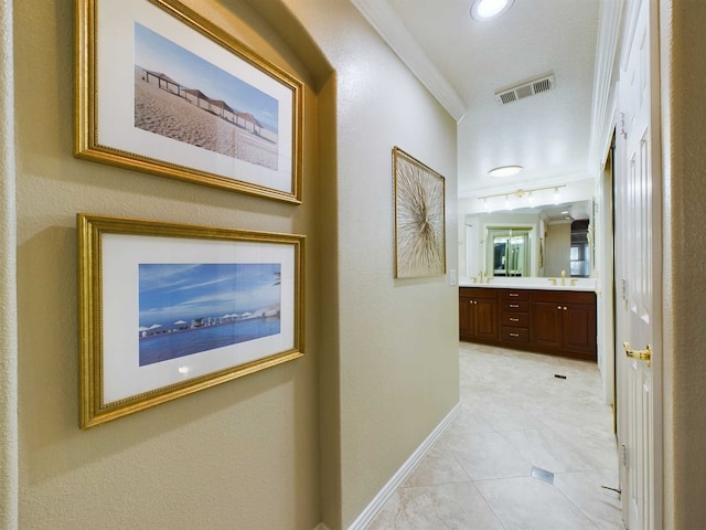 hallway with sink, light tile patterned floors, and crown molding