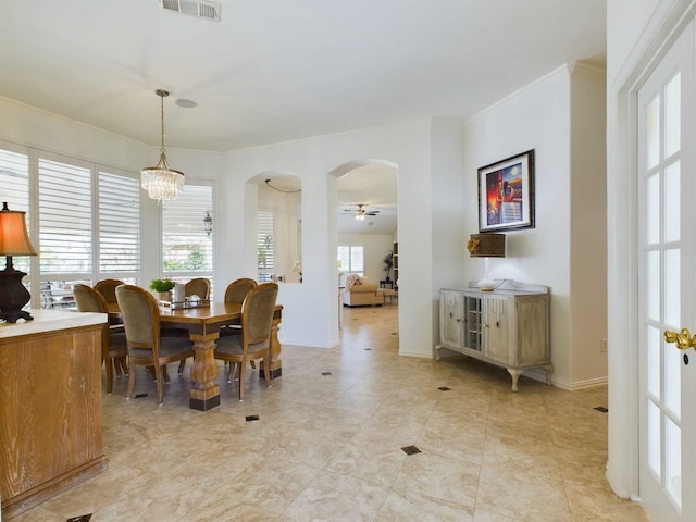 dining area with ceiling fan with notable chandelier and crown molding