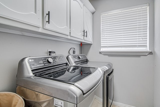 clothes washing area with washing machine and dryer and cabinets