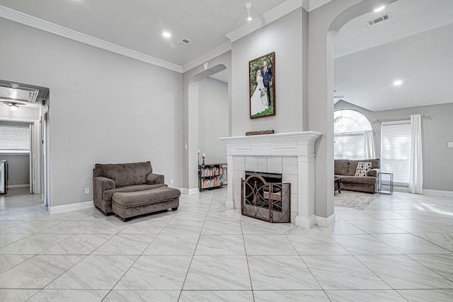 living room with a tiled fireplace and crown molding