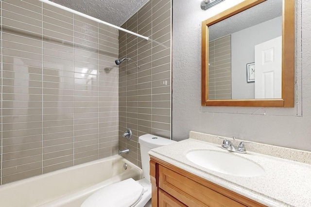 full bathroom with toilet, vanity, a textured ceiling, and tiled shower / bath