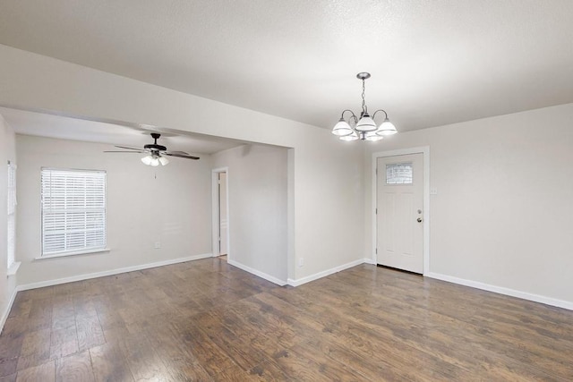 interior space featuring ceiling fan with notable chandelier and dark hardwood / wood-style flooring