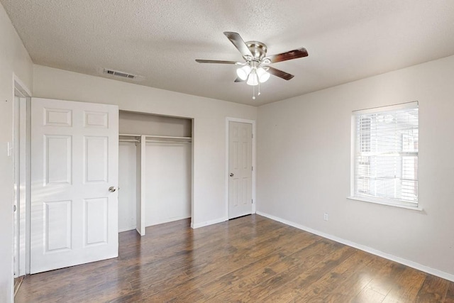 unfurnished bedroom with a textured ceiling, ceiling fan, a closet, and dark hardwood / wood-style floors