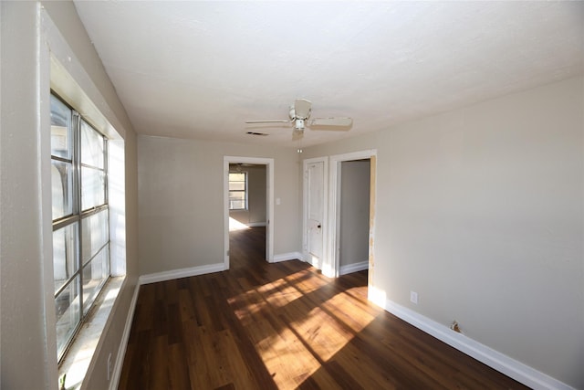 unfurnished room with dark wood-type flooring, ceiling fan, and a wealth of natural light