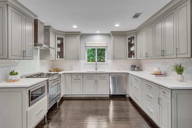 kitchen with appliances with stainless steel finishes, wall chimney exhaust hood, and gray cabinets