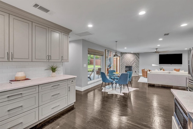 kitchen featuring light stone countertops, decorative light fixtures, backsplash, gray cabinetry, and ceiling fan