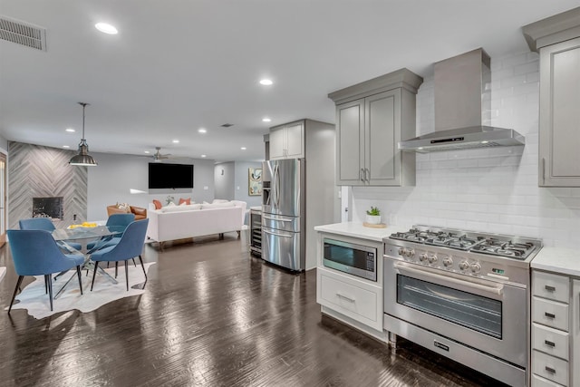 kitchen with stainless steel appliances, gray cabinets, wall chimney exhaust hood, and tasteful backsplash