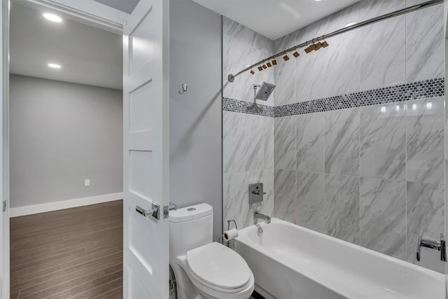 bathroom featuring toilet, wood-type flooring, and tiled shower / bath combo