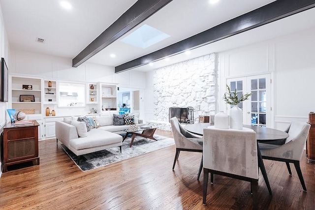 dining space featuring a fireplace, hardwood / wood-style floors, built in features, and beam ceiling