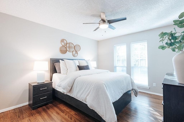 bedroom featuring ceiling fan, multiple windows, dark hardwood / wood-style floors, and a textured ceiling