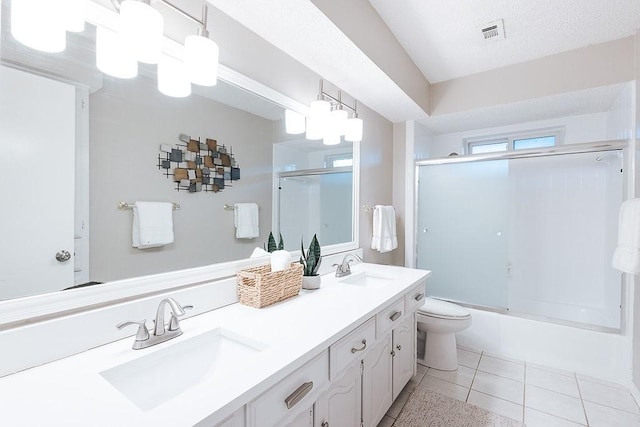 full bathroom featuring a textured ceiling, tile patterned flooring, toilet, bath / shower combo with glass door, and vanity