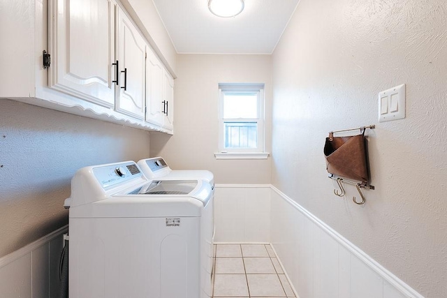 clothes washing area featuring cabinets, washing machine and dryer, and light tile patterned flooring