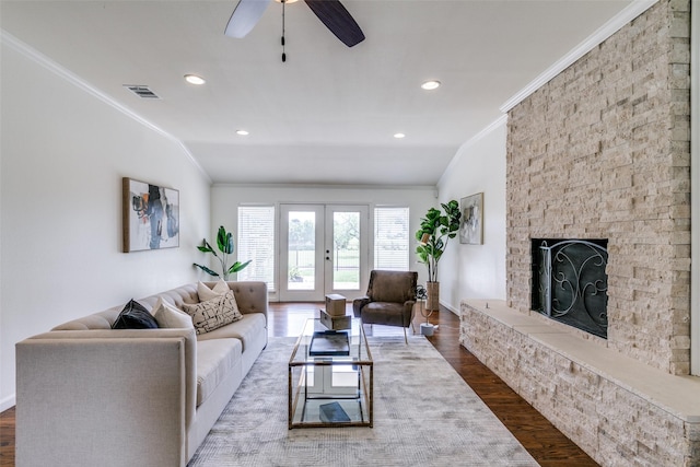 living room with lofted ceiling, french doors, wood-type flooring, and a stone fireplace