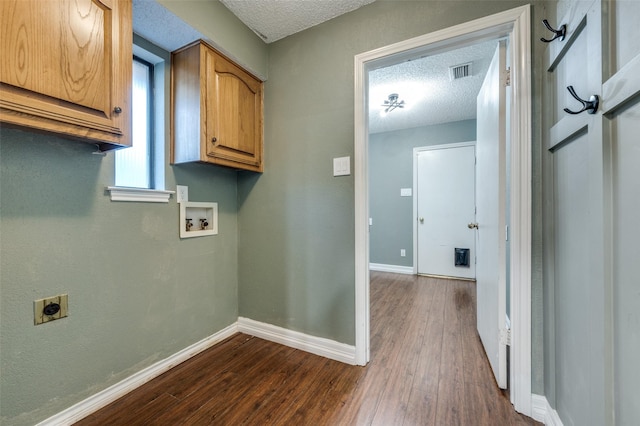 washroom with dark wood-type flooring, a textured ceiling, electric dryer hookup, cabinets, and washer hookup