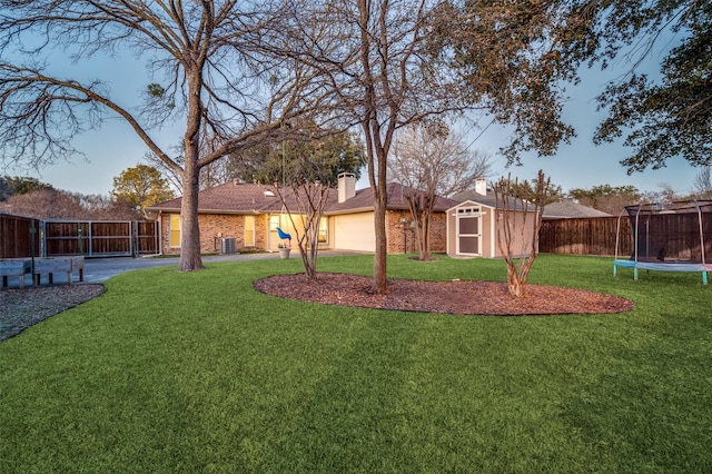 view of yard with central air condition unit, a shed, and a trampoline