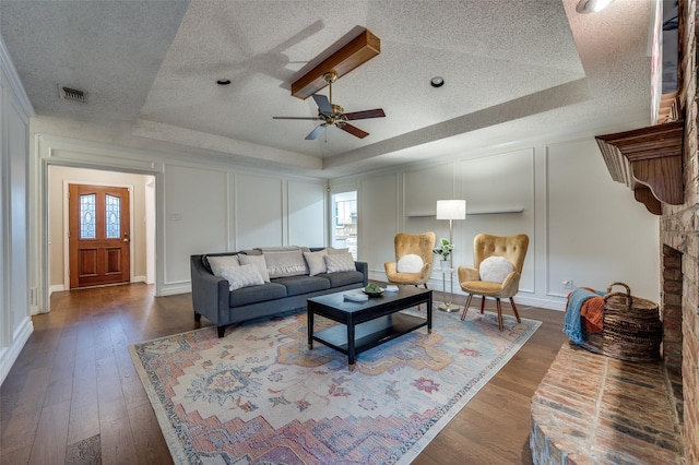 living room with ceiling fan, a tray ceiling, and dark hardwood / wood-style floors